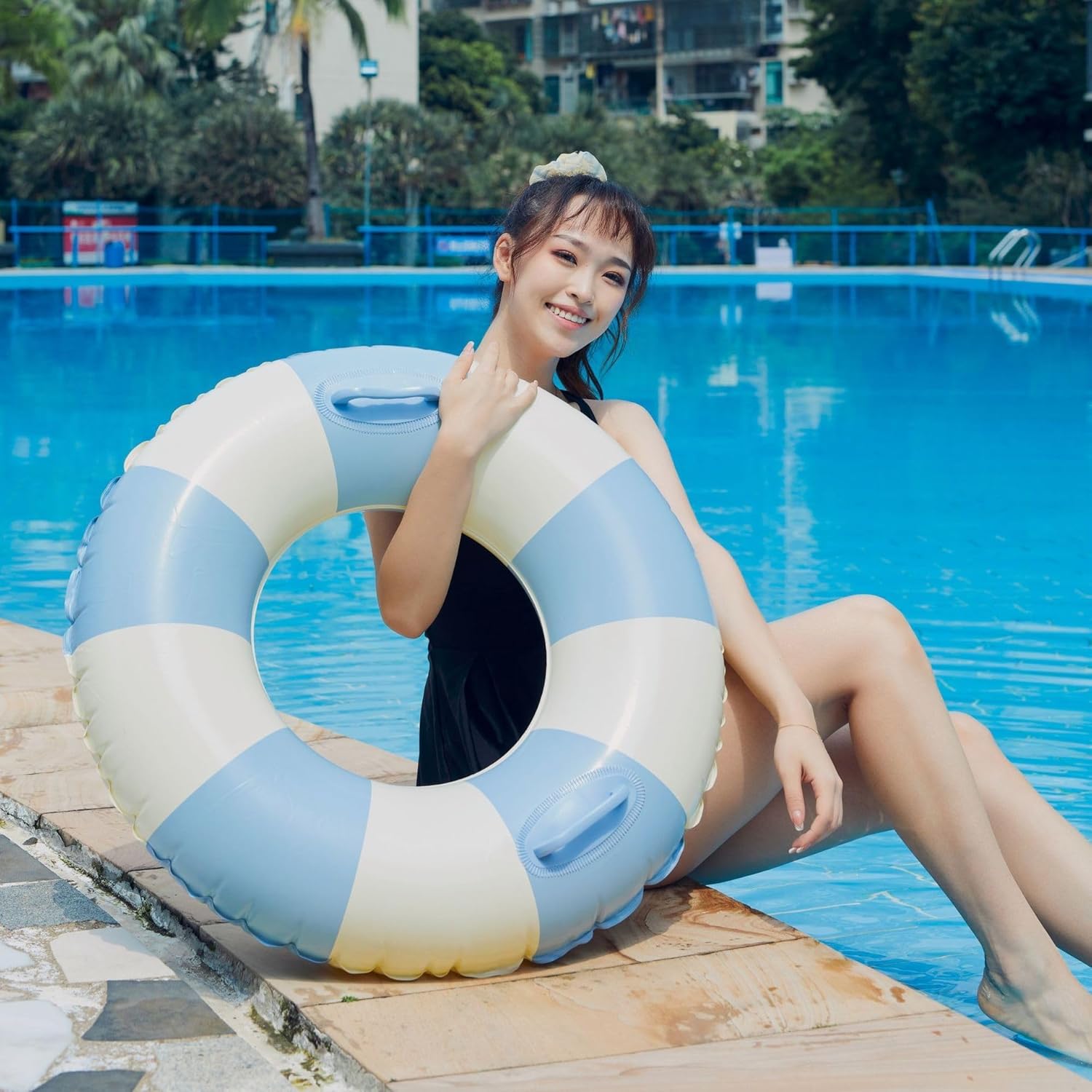 Liveify blue and white striped inflatable pool float with handles, held by woman at poolside