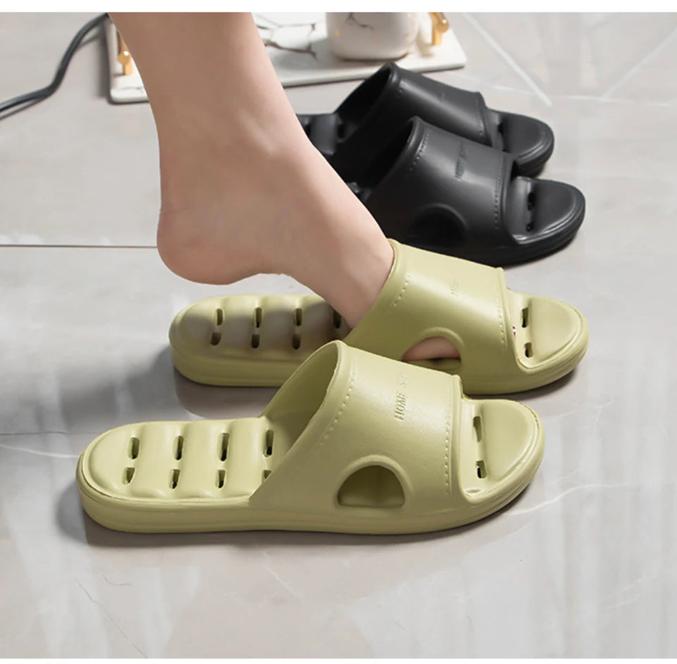 Liveify light green and black slide sandals with ventilation holes, shown on tiled floor with foot stepping in