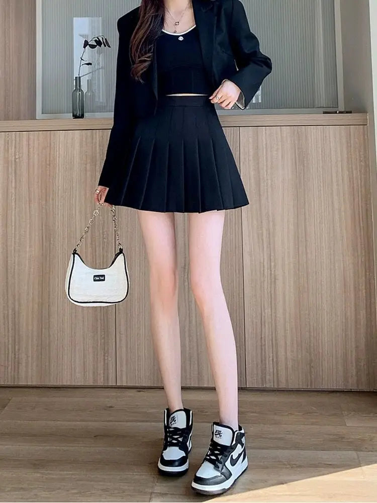 Liveify black pleated mini skirt with blazer, white bag, and high-top sneakers for trendy women's fashion