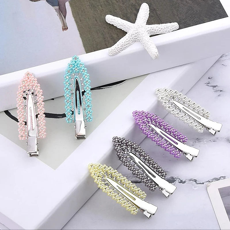 Liveify pearl and rhinestone hair clips in pink, blue, purple, gray, and yellow, styled on white marble with starfish decor