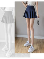 Liveify navy blue pleated tennis skirt with high waist, worn with white sneakers and star-print top