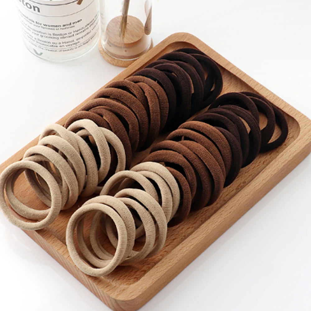 Liveify soft velvet hair ties in beige and brown shades, neatly arranged on a wooden tray for stylish hair styling.