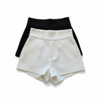 Liveify white and black high-waisted shorts with belt detail, stylish women's fashion on beige couch