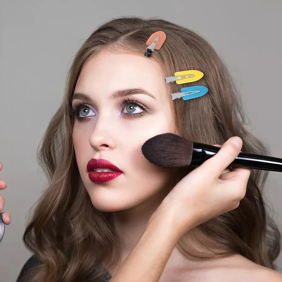 Liveify woman applying makeup with brush, colorful hair clips in hair, beauty essentials