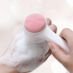 Liveify pink silicone facial cleansing brush with white handle, creating lather on hand for gentle skincare