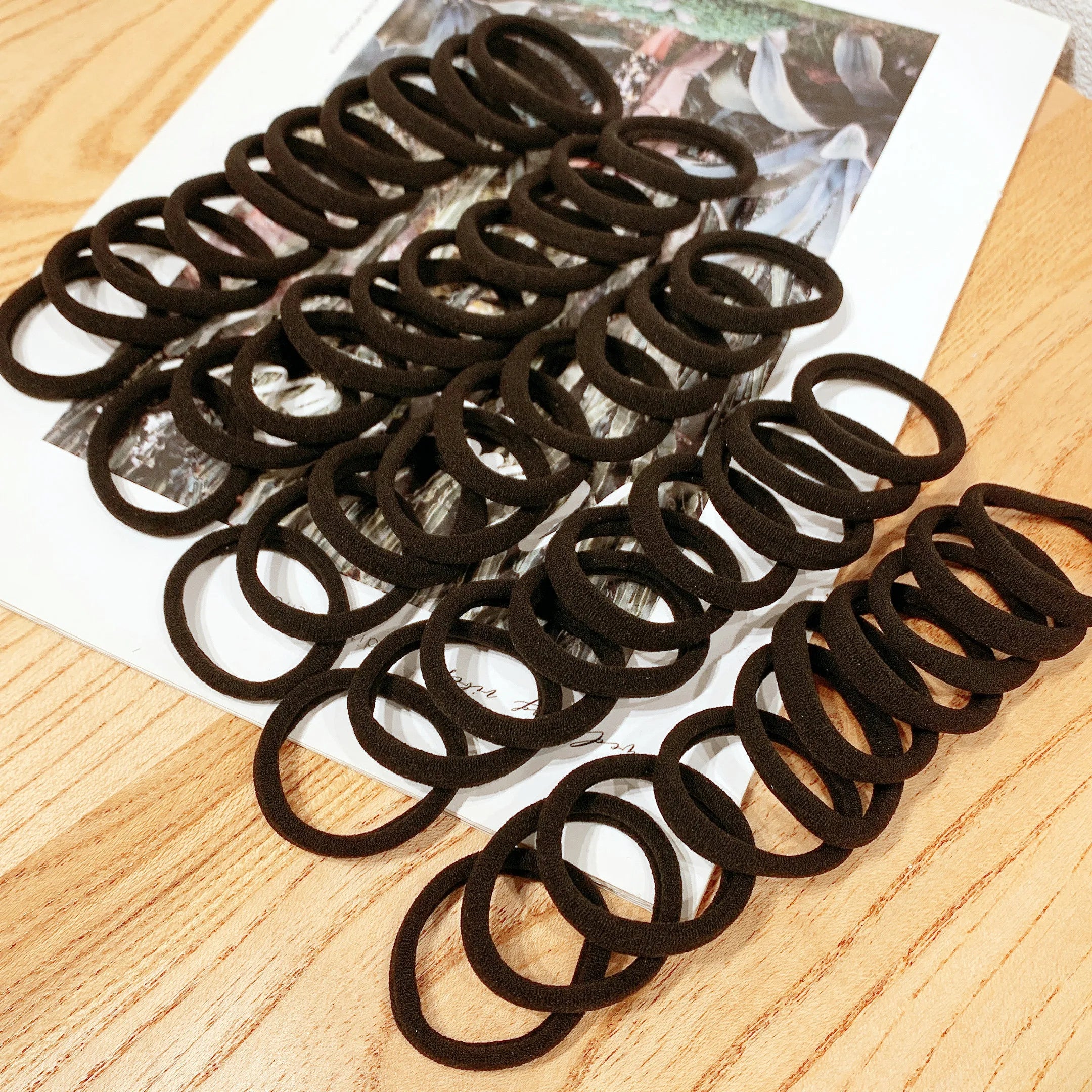 Liveify black velvet hair ties on wooden table over magazine, soft elastic ponytail holders