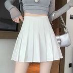 Liveify white pleated mini skirt with high waist, paired with gray crop top and silver handbag