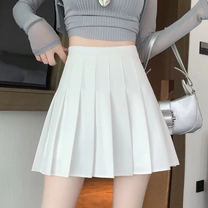 Liveify white pleated mini skirt with high waist, paired with gray crop top and silver handbag