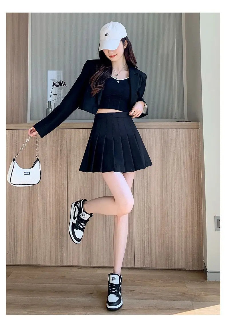 Liveify black pleated mini skirt with matching blazer, white cap, and Nike sneakers for trendy streetwear look