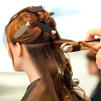 Liveify black and beige hair clips holding sections of brown hair during styling with a curling iron