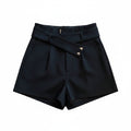 Liveify black high-waisted shorts with button details, styled on a beige couch