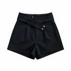 Liveify black high-waisted shorts with button details, styled on a beige couch