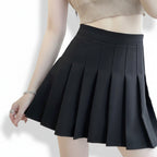 Liveify black pleated mini skirt with high waist, worn with ribbed crop top, stylish women's fashion
