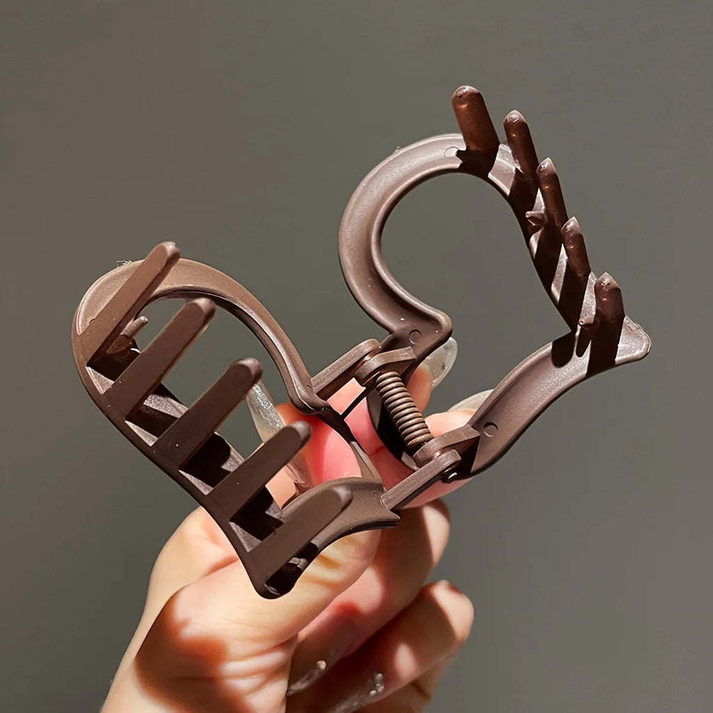 Liveify brown plastic hair claw clip with spring mechanism held in hand
