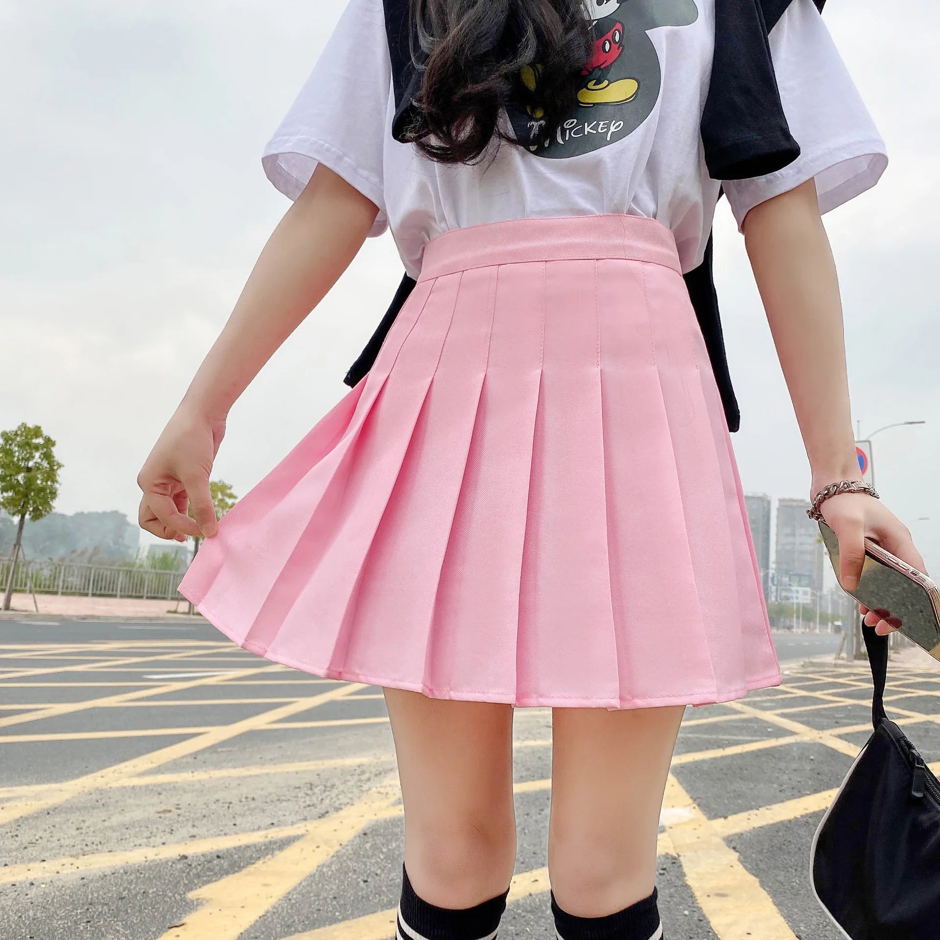 Liveify pink pleated mini skirt with high waist, worn with white graphic tee and black socks, street style