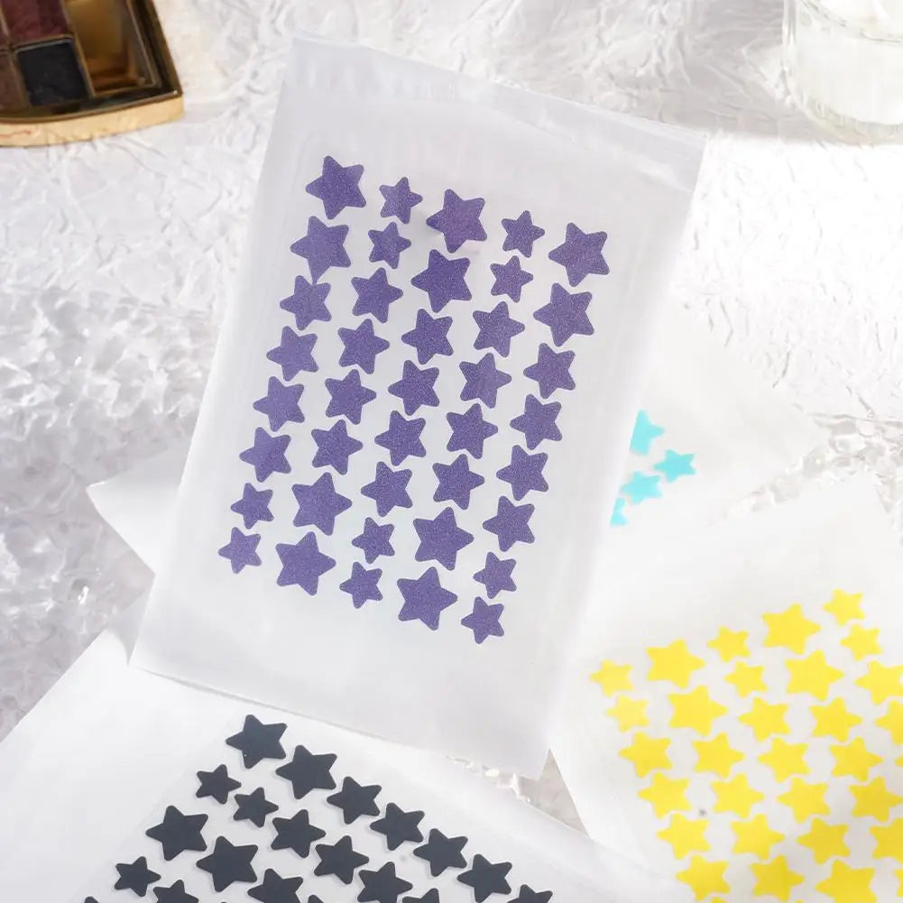 Liveify purple glitter star stickers on white sheets, with black and yellow star stickers nearby
